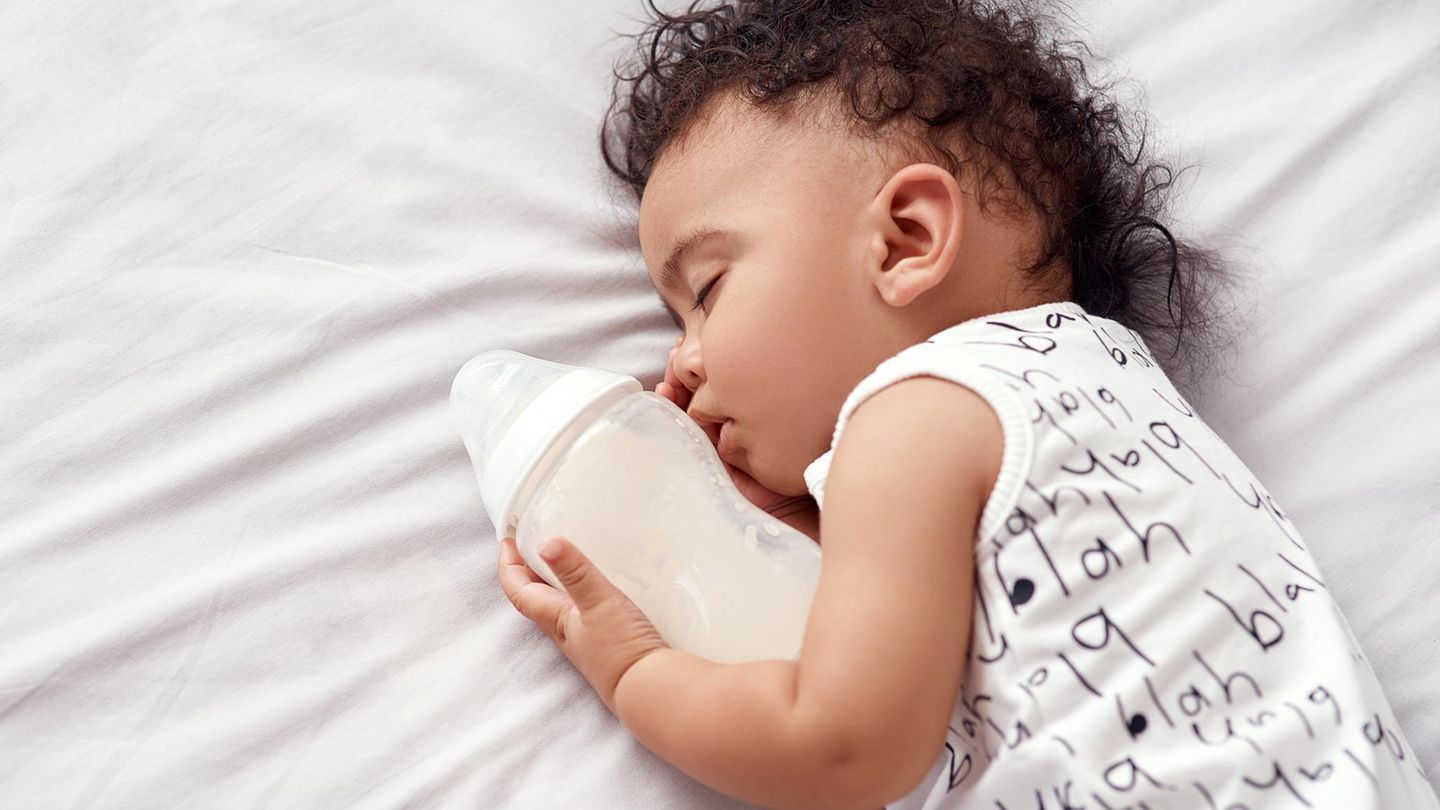 Muttermilch: Baby hält Flasche im Arm Muttermilch: Baby hält Flasche im Arm