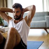 Ein man macht Bauchaufzüge in seinem Wohnzimmer