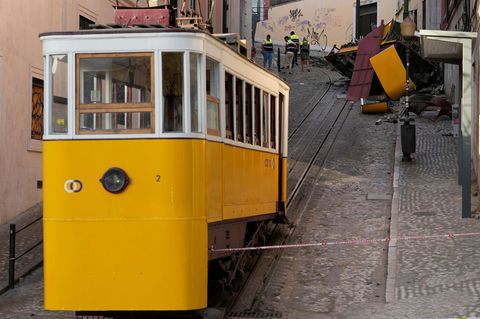 Ein gelb-weißer Waggon der Standseilbahn Lissabon steht unterhalb der Unglücksstelle