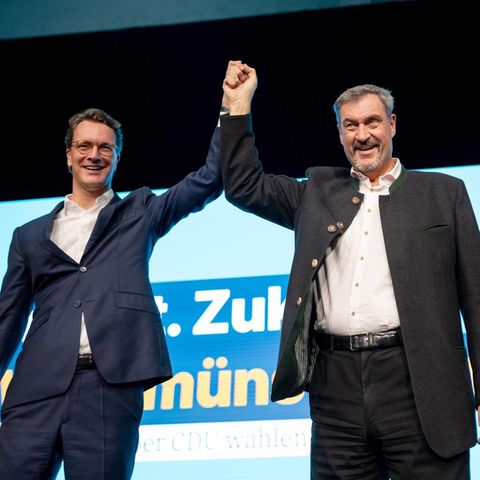 Hendrik Wüst und Markus Söder Hand in Hand auf einer Bühne