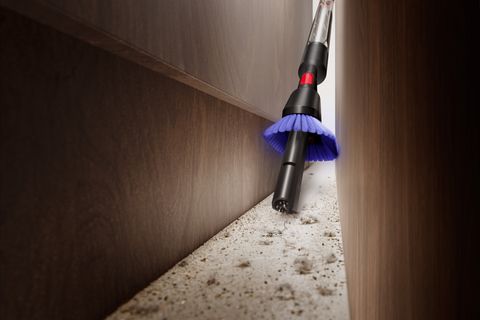 Dysons neuer Staubsauger Pencil Vac saugt in einem Spalt zwischen Möbeln