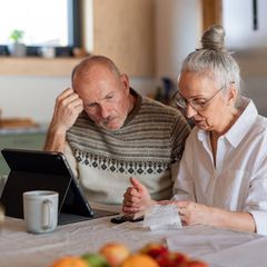 Rente: Zwei Rentner beugen sich über Unterlagen zur Steuererklärung