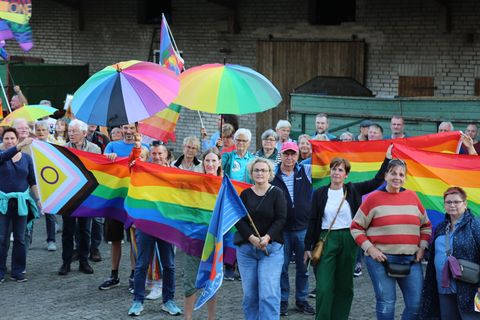 Menschen mit Regenbogenflaggen und -schirmen beteiligten sich an einer Kundgebung. Foto: Benjamin Müller/dpa