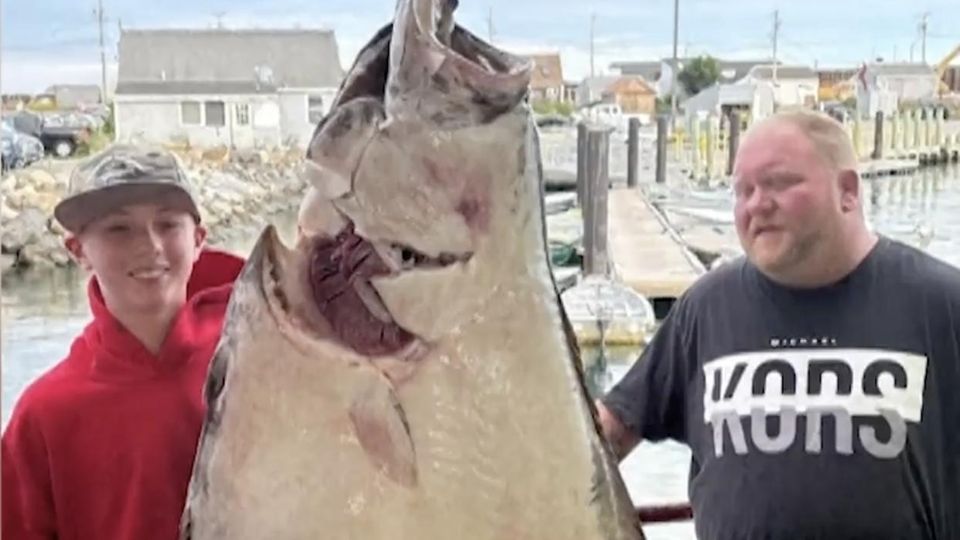 Ein junger Mann mit einem Fisch der größer als er selbst ist.