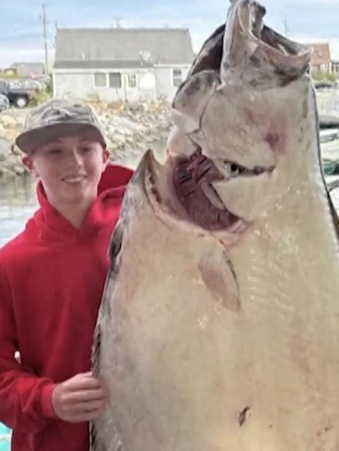 Ein junger Mann mit einem Fisch der größer als er selbst ist.