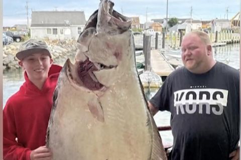 Ein junger Mann mit einem Fisch der größer als er selbst ist.