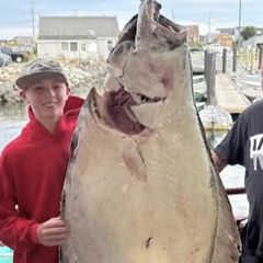 Ein junger Mann mit einem Fisch der größer als er selbst ist.