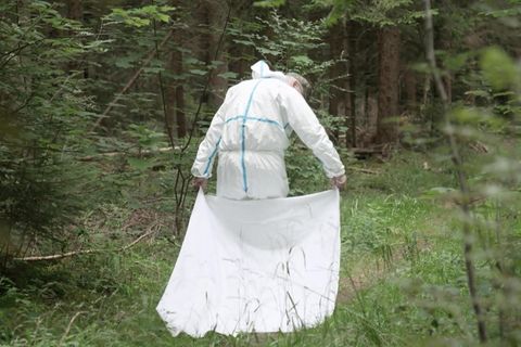 Ein Mann läuft mit einem weissen Tuch durch den Wald