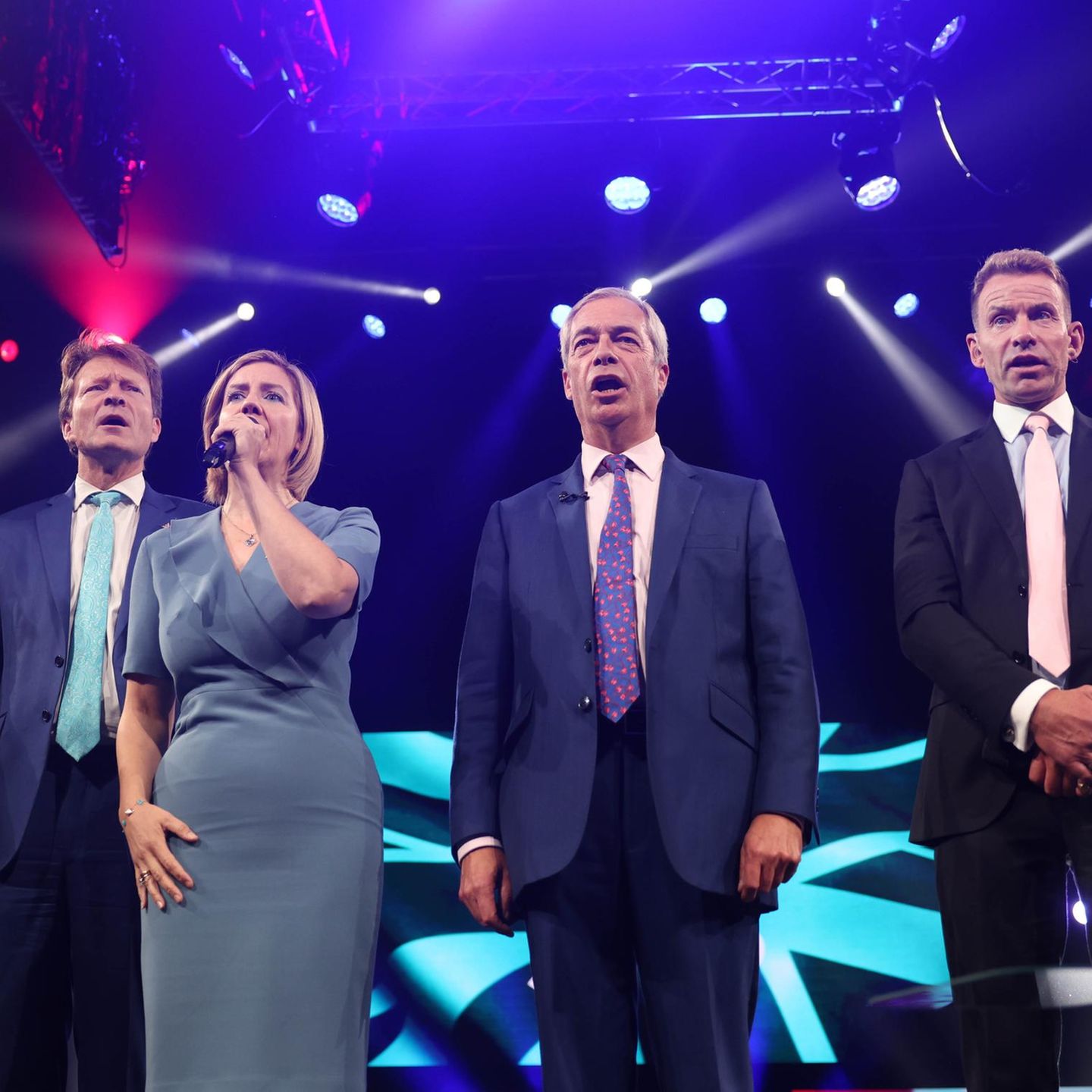Reform-Mitglieder Darren Grimes, Richard Tice, Andrea Jenkyns, Nigel Farage und David Bull (v.l.) singen zum Abschluss der Reform-Parteikonferenz in Birmingham gemeinsam die Nationalhymne 