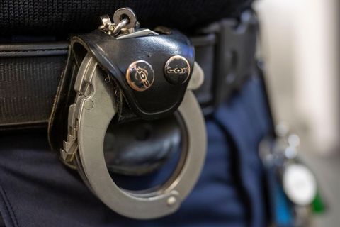 Eine Handschelle hängt am Gürtel eines Polizisten, Symbolbild Ansbach