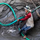 Arbeiter hantiert beim Entladen eines Baggerschiffs mit schwerem Gerät