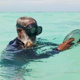 Mann mit Metallteller und einer Taucherbrille im Meer