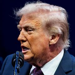 Donald Trump spricht in ein Mikrofon und schaut ernst