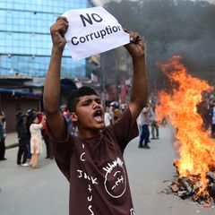 Ein Demonstrant in Nepal mit einem Schild, auf der er ein Ende der Korruption fordert