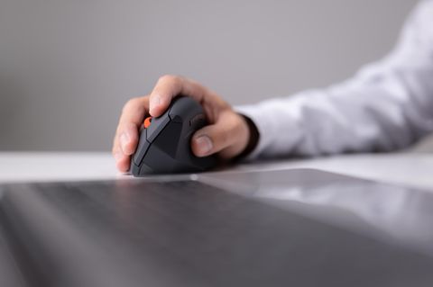Ein Mann nutzt eine ergonomische Maus im Büro