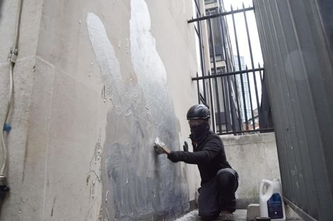 Eine Person schrubbt das neueste Kunstwerk des britischen Künstlers Banksy an den Royal Courts of Justice ab