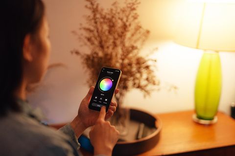 Eine Frau bedient ihre Philips-Hue-Alternative mit dem Smartphone