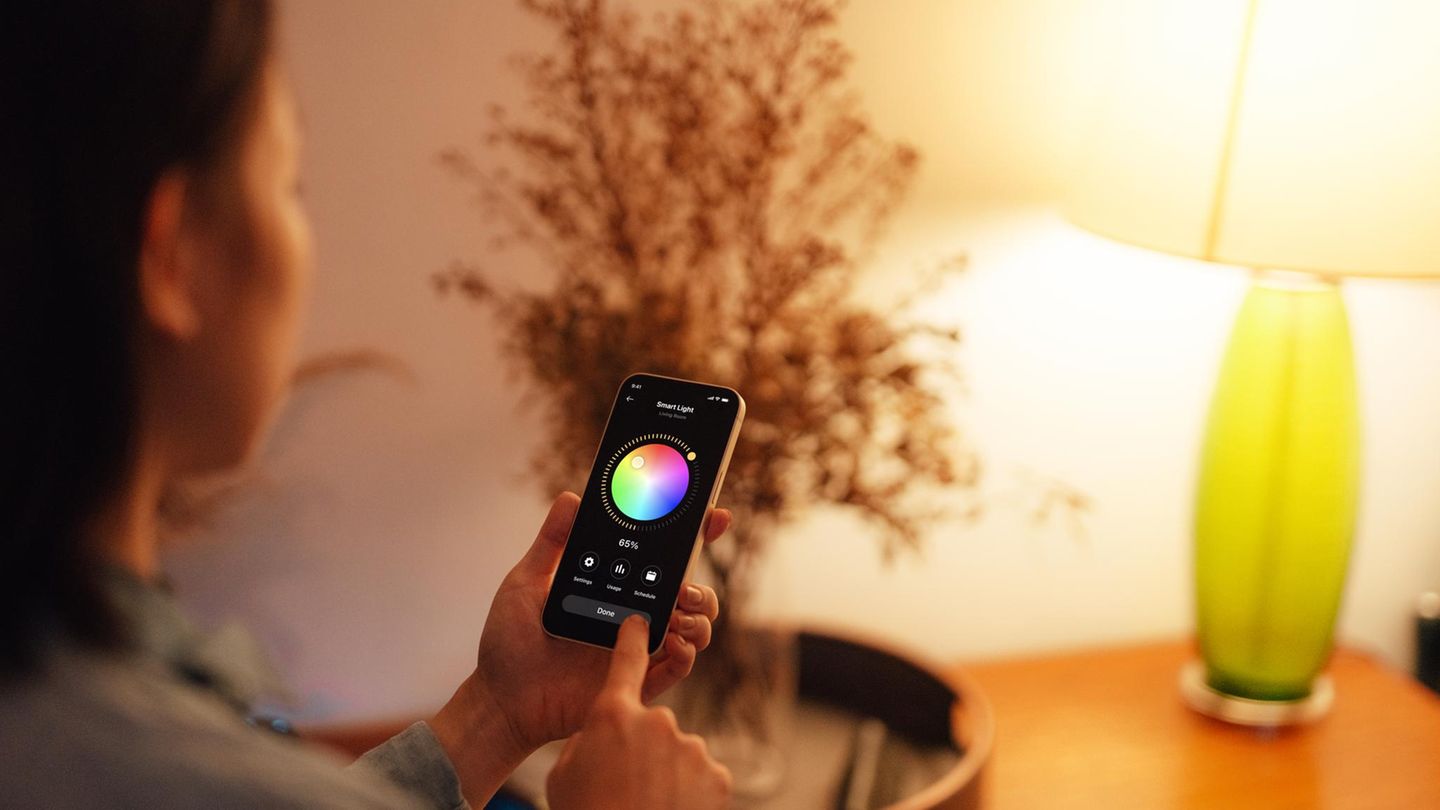 Eine Frau bedient ihre Philips-Hue-Alternative mit dem Smartphone