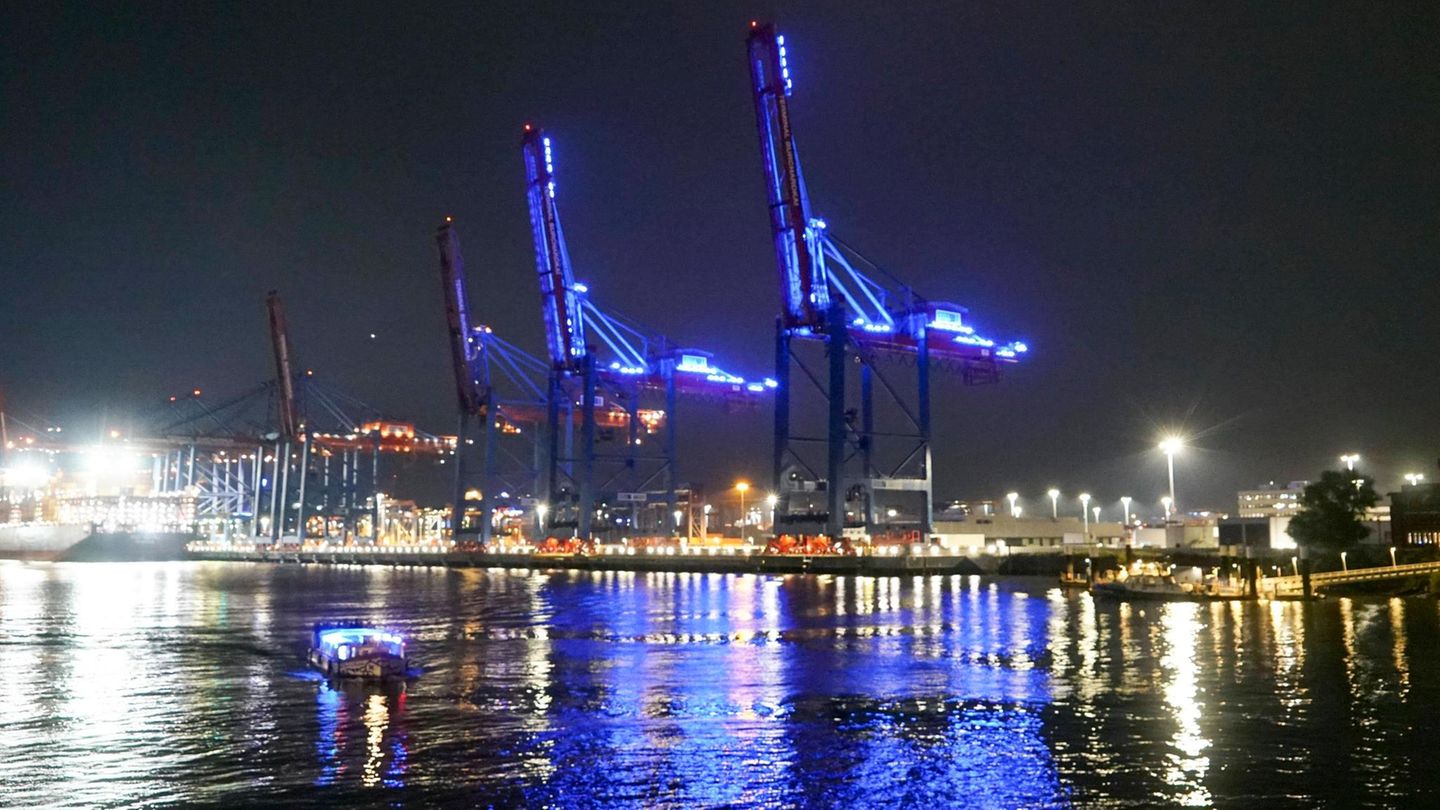 Hafenkräne in Hamburg sind bei Nacht in blaues Licht getaucht