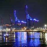 Hafenkräne in Hamburg sind bei Nacht in blaues Licht getaucht