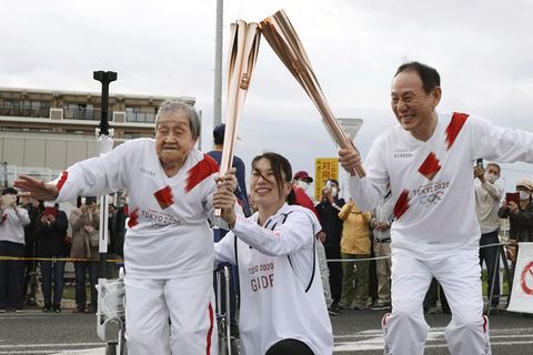 Fackelläuferin Shigeko Kagawa übergibt die Fackel während eines Fackellaufs für die Olympischen Spiele Japan