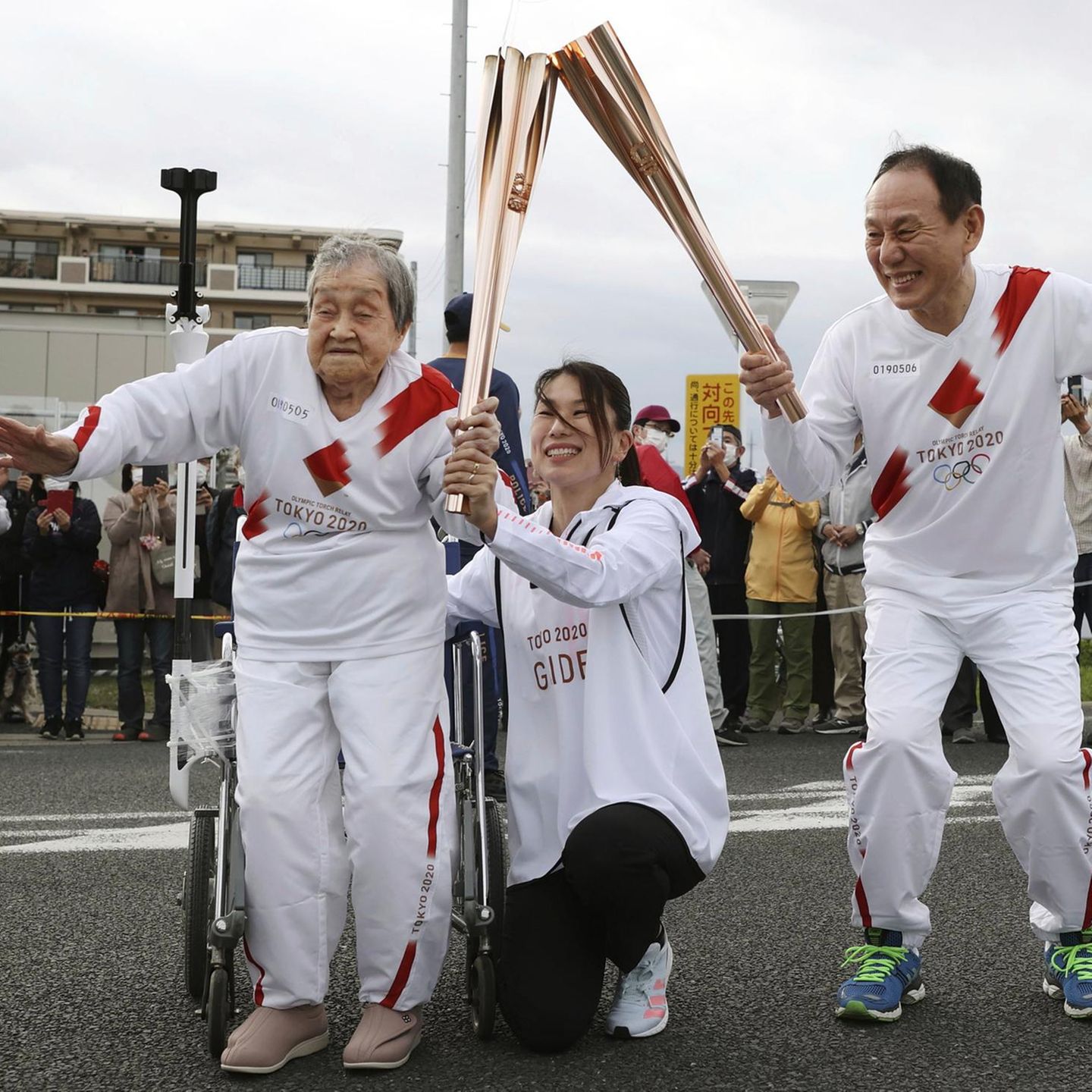 Fackelläuferin Shigeko Kagawa übergibt die Fackel während eines Fackellaufs für die Olympischen Spiele Japan