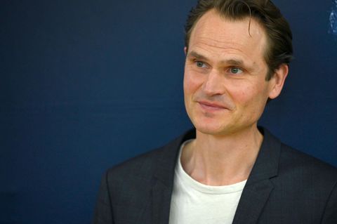 Fabian Hinrichs, ein Mann mit Welle über der Stirn, schaut leicht zur Seite