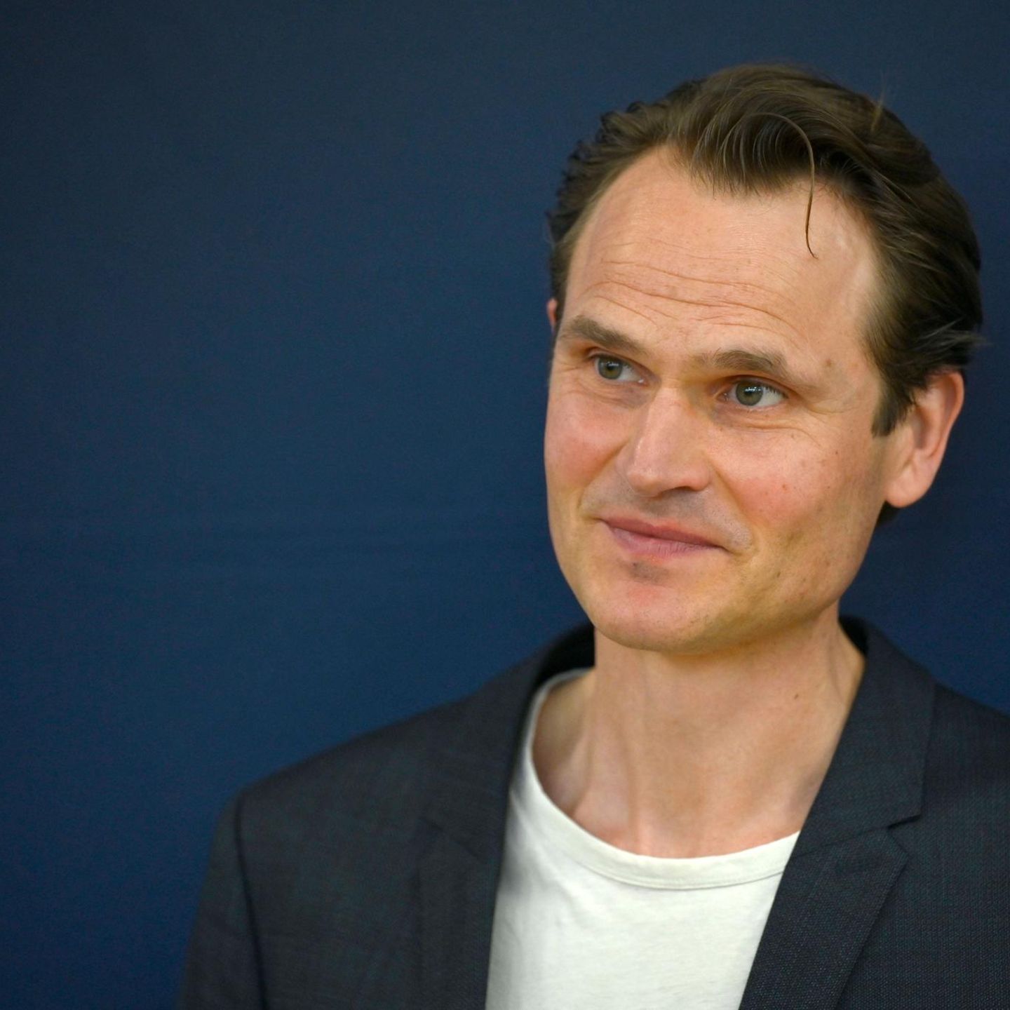 Fabian Hinrichs, ein Mann mit Welle über der Stirn, schaut leicht zur Seite