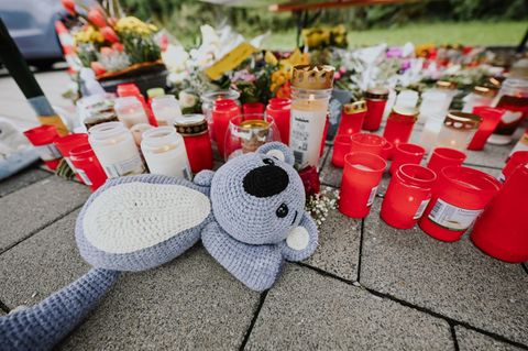 Menschen legen Blumen und Kerzen auf dem abgesperrten Parkplatz in Niedernhall nieder. Foto: Marius Bulling/dpa