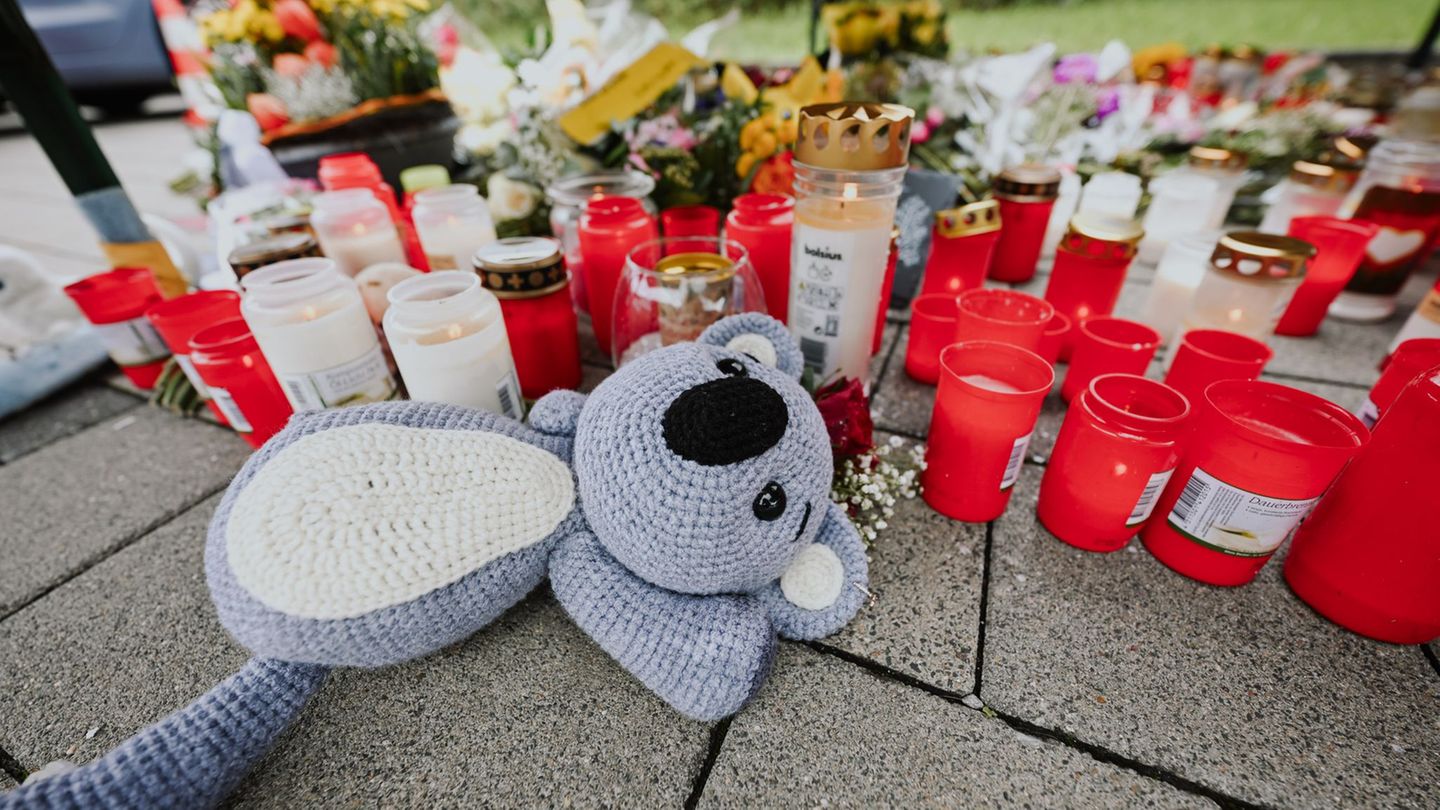 Menschen legen Blumen und Kerzen auf dem abgesperrten Parkplatz in Niedernhall nieder. Foto: Marius Bulling/dpa