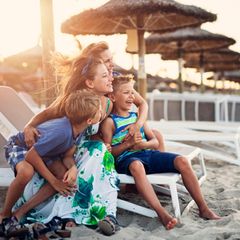 Auswandern Symbolbild: Fröhliche Familie am Strand