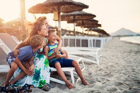 Auswandern Symbolbild: Fröhliche Familie am Strand