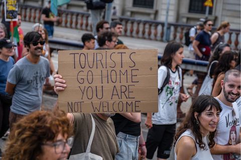 Menschen protestieren im Juli in Barcelona mit Schildern gegen Massentourismus
