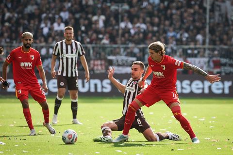 Im Zweikampf: Kristijan Jakić vom FC Augsburg (r) und St. Paulis James Sands. Foto: Christian Charisius/dpa