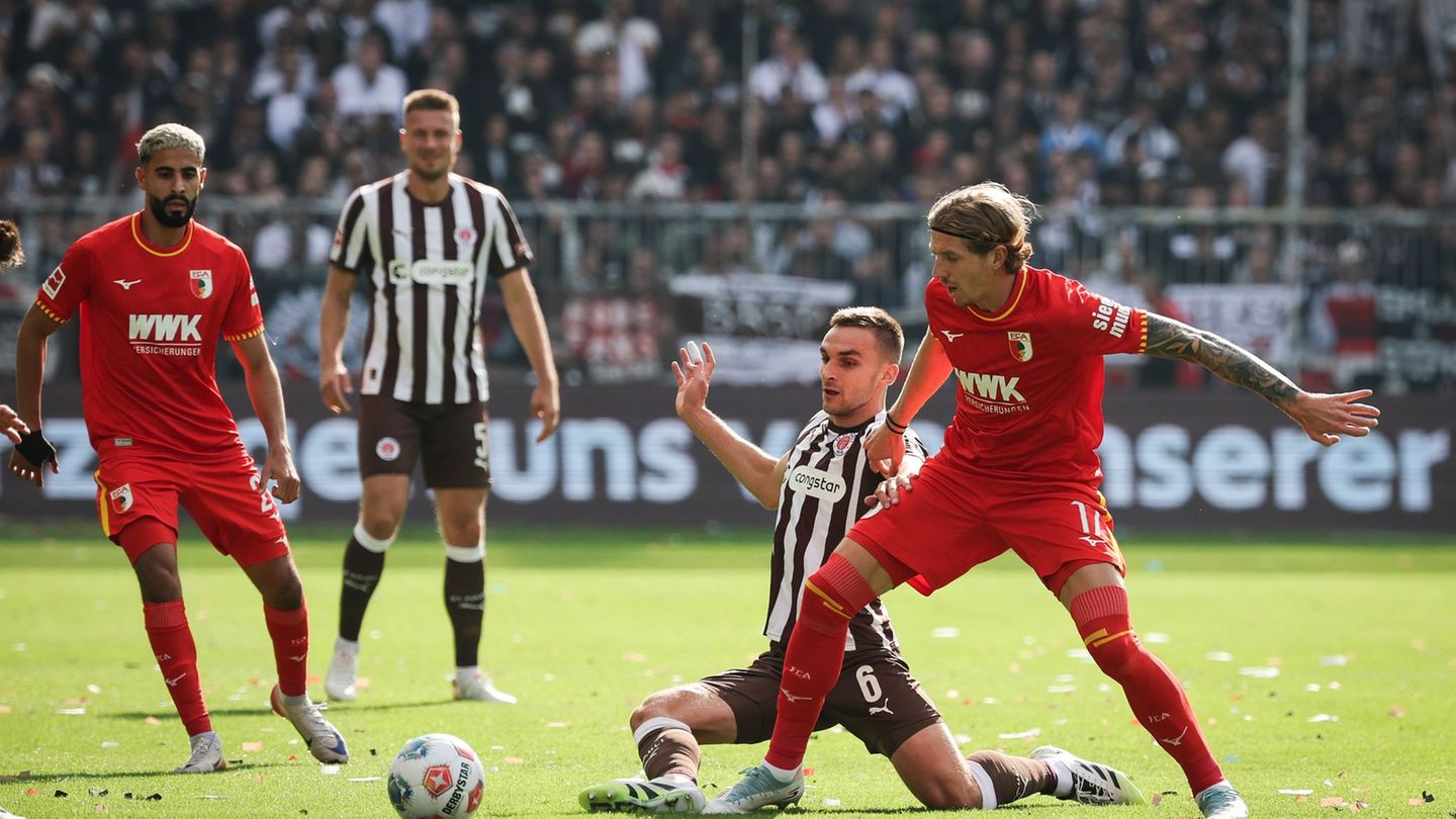 Im Zweikampf: Kristijan Jakić vom FC Augsburg (r) und St. Paulis James Sands. Foto: Christian Charisius/dpa