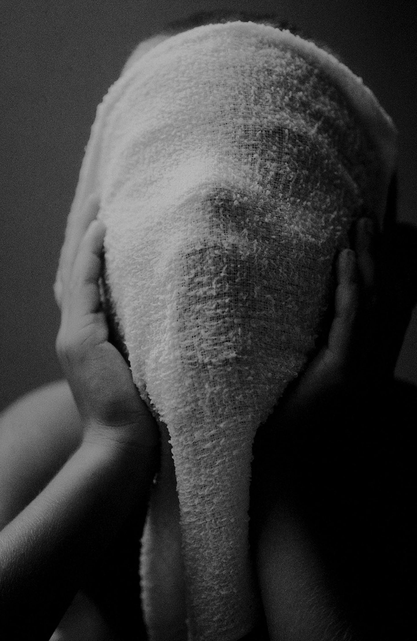 Fotografie: Ein Kind hält sich ein Handtuch vor das Gesicht und hält es mit den Händen. Der Mund ist weit offen