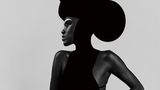 Fotografie: Eine Person trägt ein schwarzes Kleid und einen runden schwarzen Hut. Sie macht eine elegante Pose