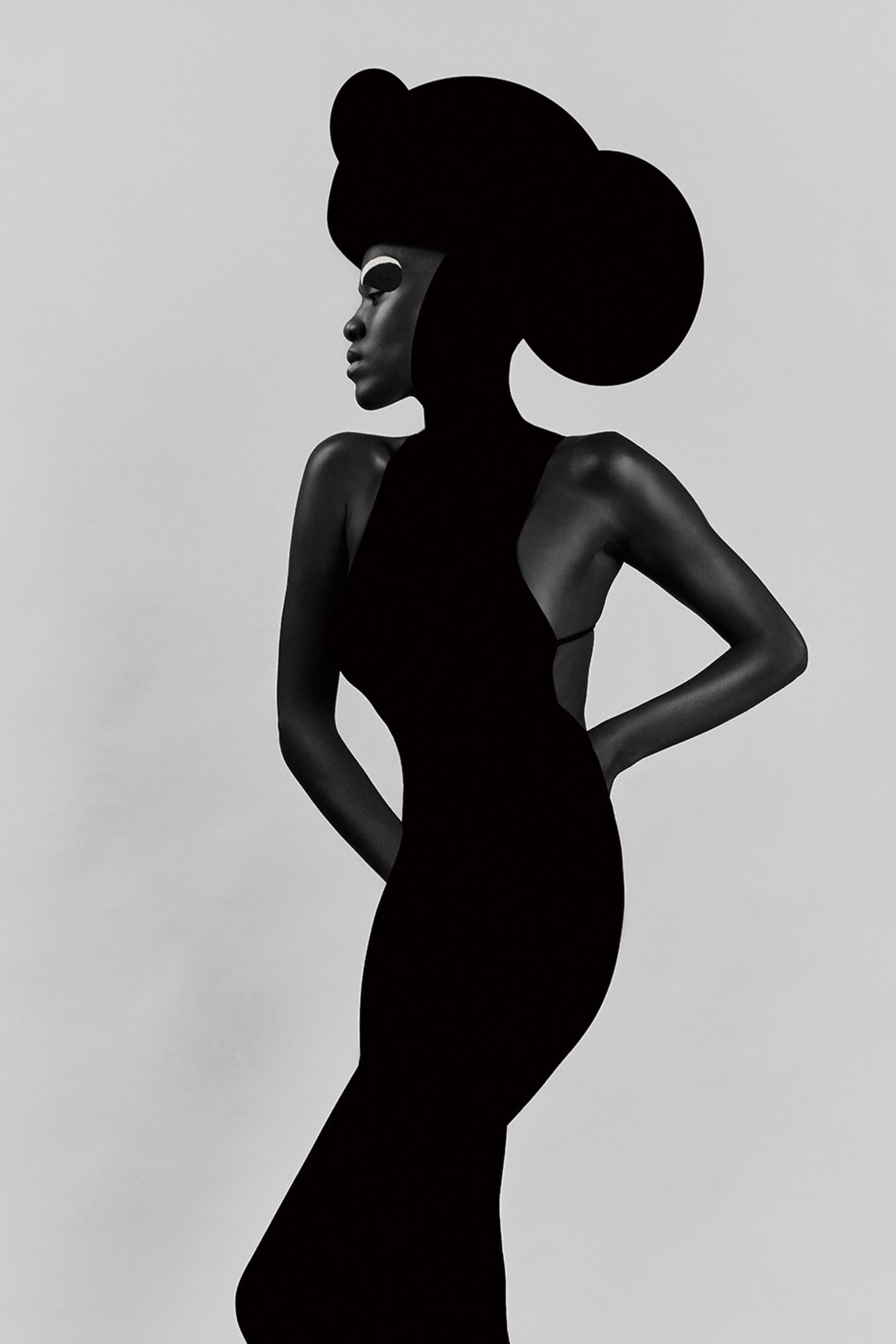 Fotografie: Eine Person trägt ein schwarzes Kleid und einen runden schwarzen Hut. Sie macht eine elegante Pose