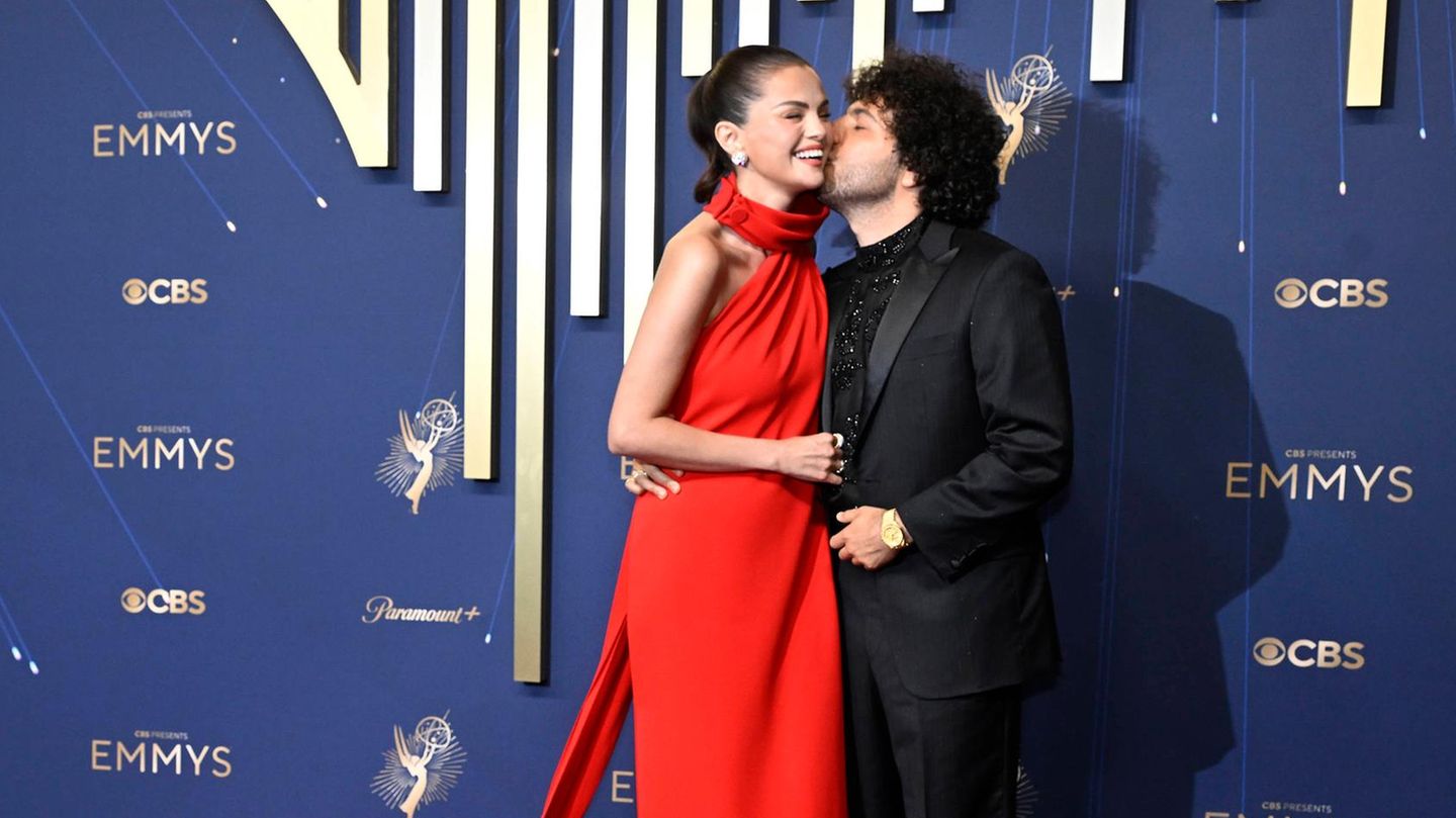 Emmy: Selena Gomez im roten Kleid mit Mann, der sie auf die Wange küsst