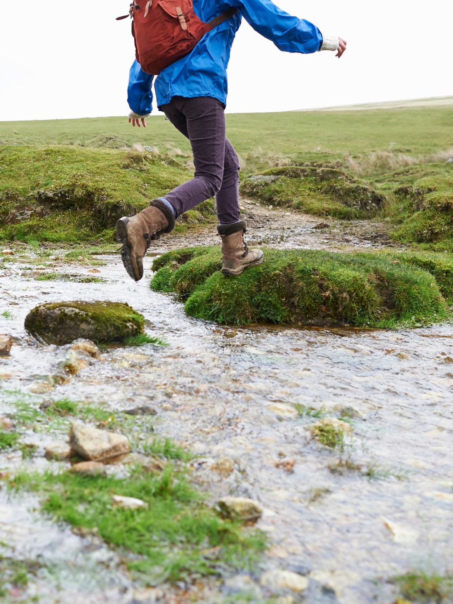 Two hikers step across the rocks in a small stream
