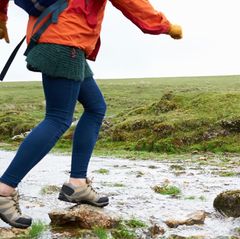 Two hikers step across the rocks in a small stream