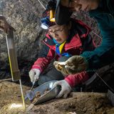Steinzeit Forscher trägt mit einer Kelle Bodenpartikel ab