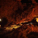 Steinzeit Mann und Frau mit Stirnlampen übergeben sich ein Fundstück