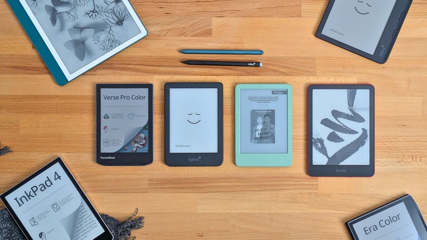 Sieben E-Book-Reader liegen auf einem hellen Holztisch