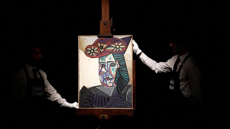 Zwei Angestellte des Aktionshauses präsentieren "Büste einer Frau mit Blumenhut" von Pablo Picasso