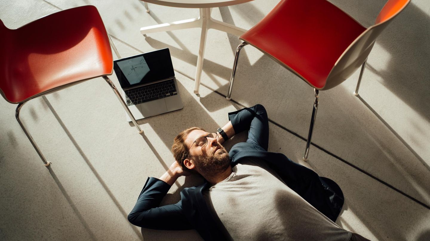 Erschöpfung: Mann liegt mit Laptop auf dem Boden
