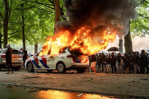 Randalierer zünden ein Polizeiauto in Den Haag an.