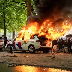 Randalierer zünden ein Polizeiauto in Den Haag an.