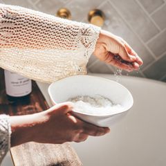 Frau streut Badesalz in die Badewanne