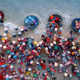 Meeresfotografie: Eine Menschenmenge von oben, die das Gefischte an Land befördert